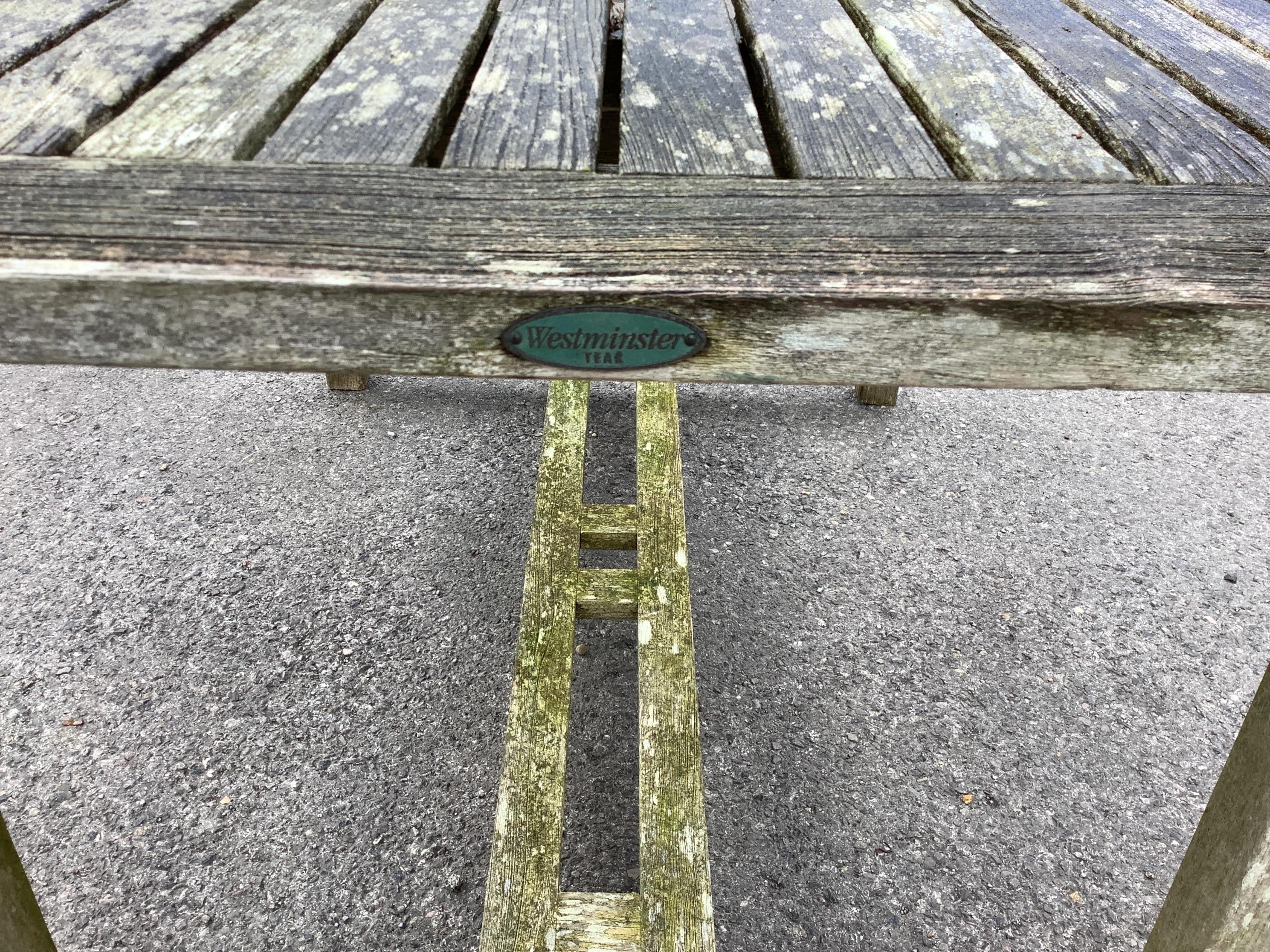 A Westminster rectangular weathered teak extending garden table, width 140cm, depth 90cm, height 73cm, (leaves inoperable), together with a pair of teak folding garden chairs. Condition - fair